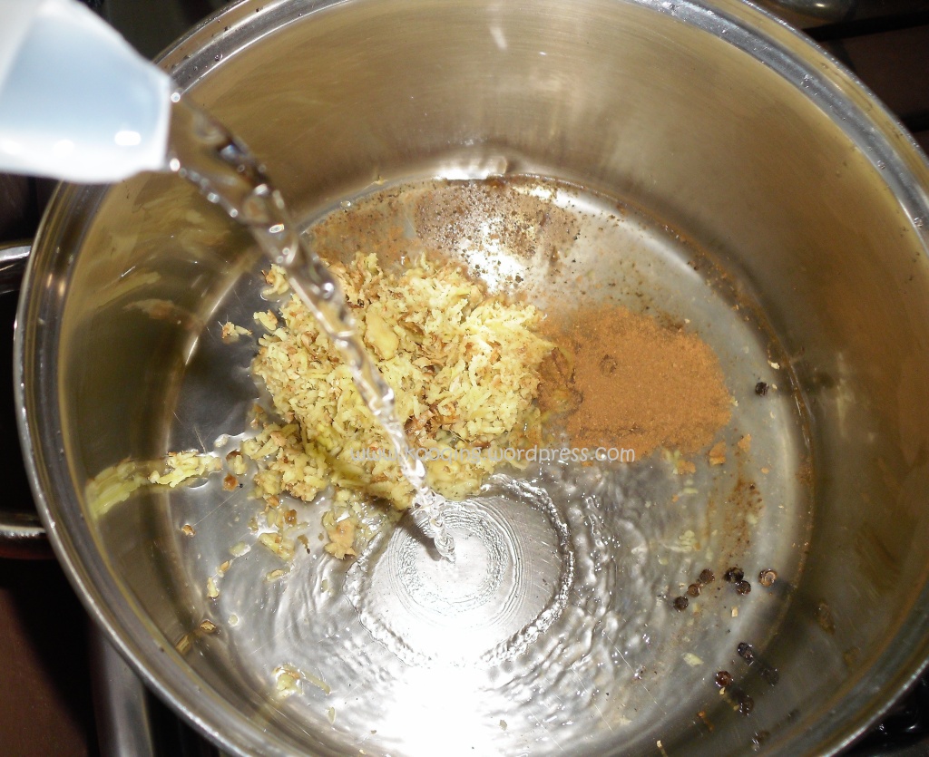 Clear water being poured in a saucepan of spices; a step in how to make african tea.
