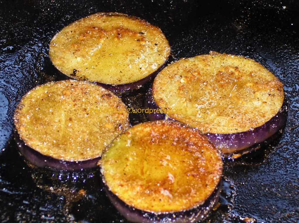 How to make fried aubergine bruschetta; a frying pan with golden brown aubergine slices 