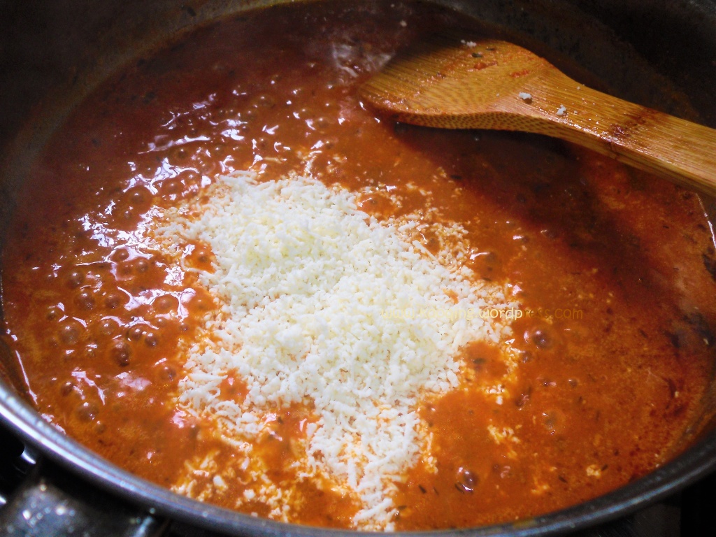 Stirring the cream and mozzarella into the saute pan containing tomato sauce 
